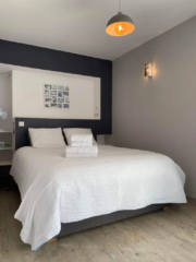 Chambre parentale avec grand lit double, mur anthracite et lumière douce au Mas du Camisard, gîte de charme dans le Gard