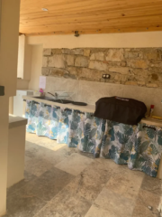 Cuisine d’été ombragée sous voûte en pierre, avec bar rustique et ambiance méridionale au Mas du Camisard, maison de vacances dans le Gard