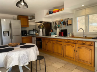 Cuisine équipée avec grand plan de travail, table ronde et électroménager complet au Mas du Camisard, gîte de charme dans le Gard