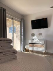 Chambre lumineuse avec grand lit, télévision murale et accès direct à la terrasse au Mas du Camisard dans le Gard