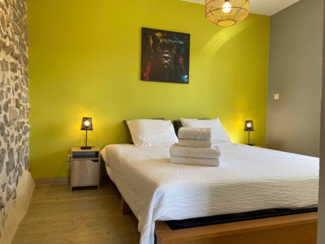 Chambre chaleureuse avec mur en pierre et mur jaune vif, grand lit double et ambiance naturelle au Mas du Camisard