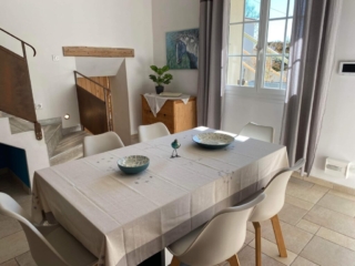 Table dressée pour six personnes dans une salle à manger lumineuse avec vue sur le jardin, au Mas du Camisard à Ribaute-les-Tavernes, dans le Gard