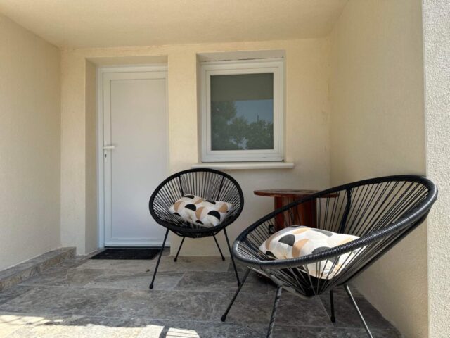 Espace détente en plein air du Mas du Camisard avec deux fauteuils noirs design et coussins colorés, ambiance moderne et reposante