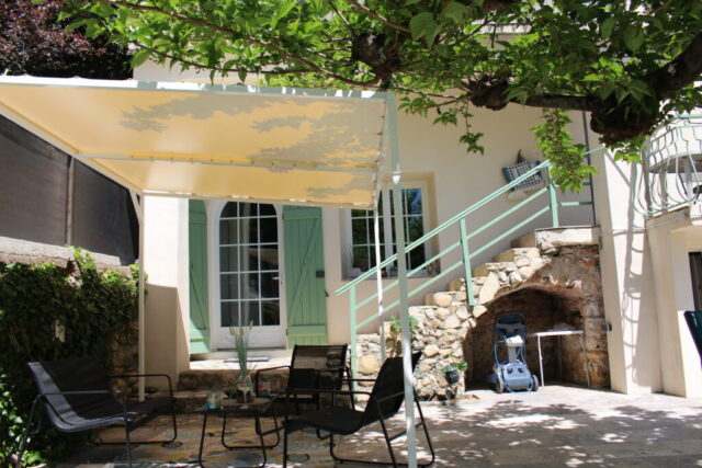 Terrasse ombragée avec mobilier de jardin et escalier en pierre au Mas du Camisard, maison de vacances authentique dans le sud de la France