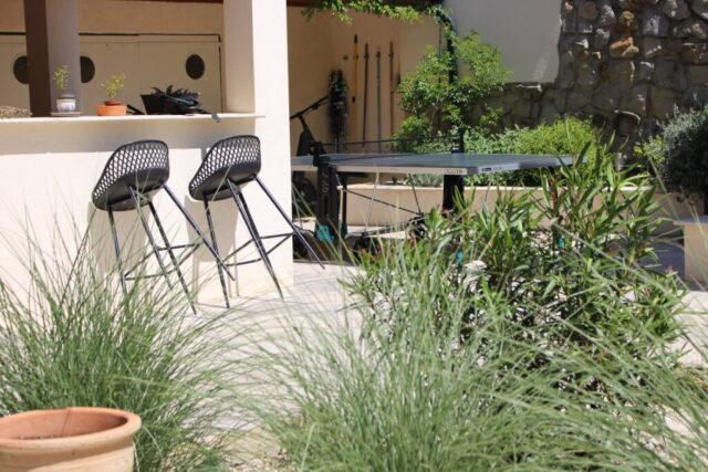 Vue sur le bar extérieur de la cuisine d’été entouré de verdure, au Mas du Camisard, maison de vacances avec terrasse dans le sud de la France