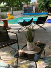 Table basse et fauteuils sur la terrasse ensoleillée du Mas du Camisard, avec vue sur la piscine et les transats, ambiance estivale en Occitanie