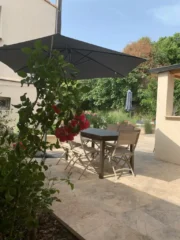 Terrasse ensoleillée avec table et parasol, donnant sur le jardin du Mas du Camisard, ambiance détente et vacances en Provence