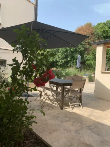 Terrasse ensoleillée avec table et parasol, donnant sur le jardin du Mas du Camisard, ambiance détente et vacances en Provence