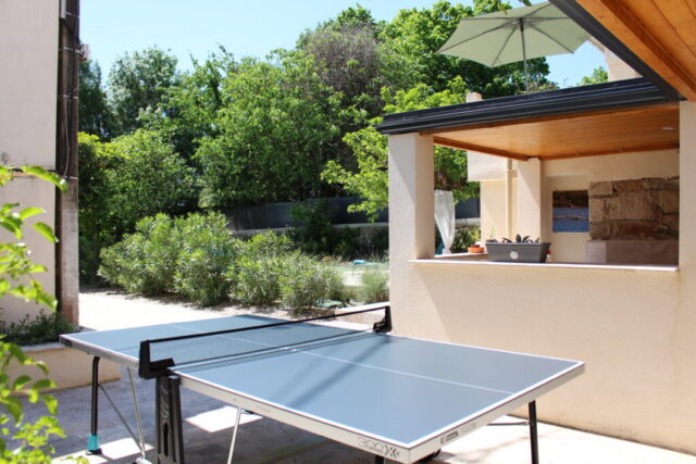 Cuisine d’été couverte et table de ping-pong extérieure dans un jardin arboré au Mas du Camisard, gîte avec activités en famille dans le sud de la France